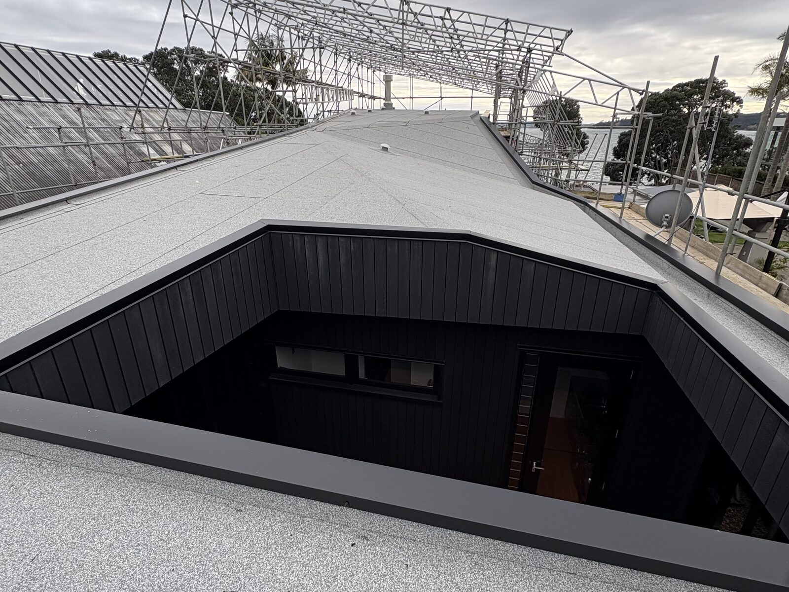 Re-roofed courtyard section with dark vertical cedar cladding, Westmere